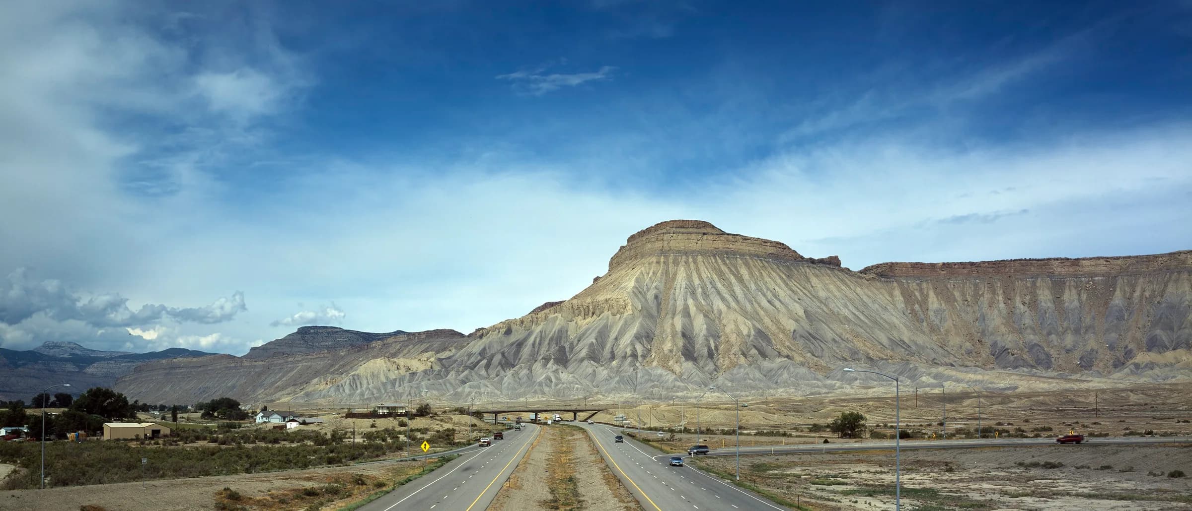 A long straight interstate running toward a flat-topped mesa across open Utah desert.